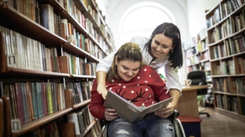 Girl in a wheelchair with a carer in the library